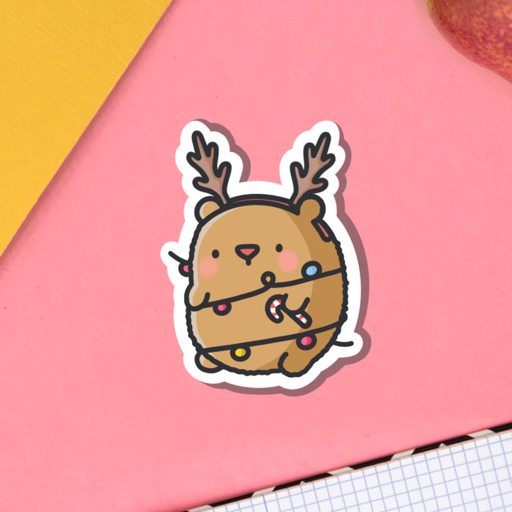 Bear dressed as reindeer vinyl sticker on pink table and notebook
