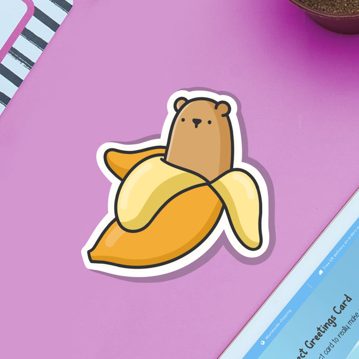 Bear in a banana vinyl sticker on purple table with ipad