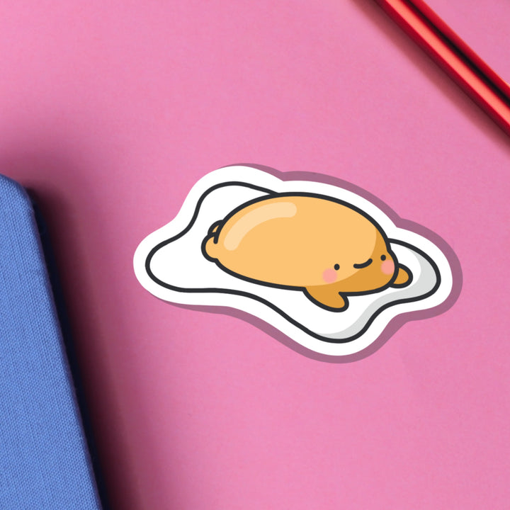 Fried egg vinyl sticker on pink table with notebook