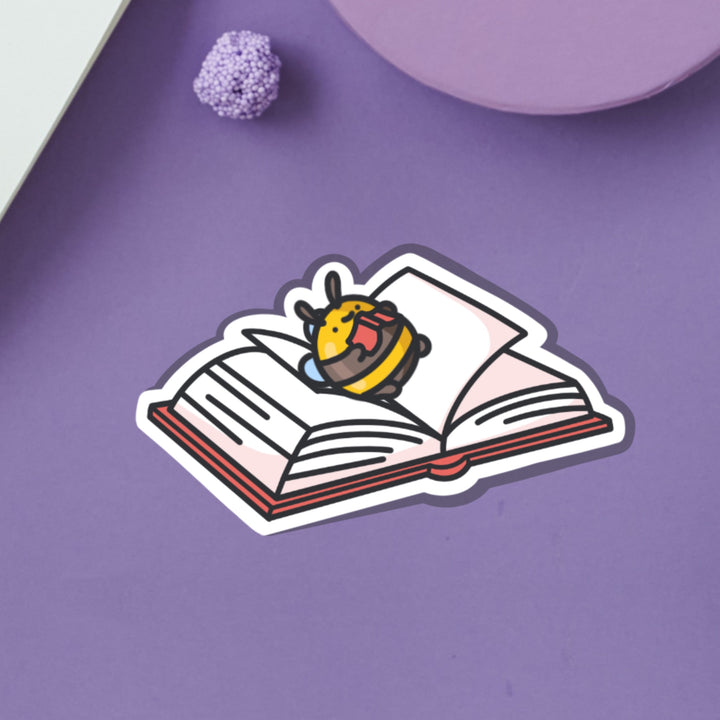 Bee lying on a book vinyl sticker on purple background