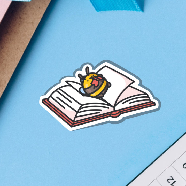 Bee lying on a book vinyl sticker on blue table
