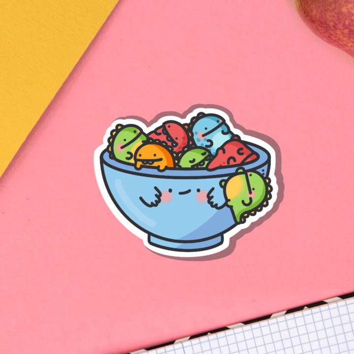 Bowl of dinosaurs vinyl sticker on pink table with notebook