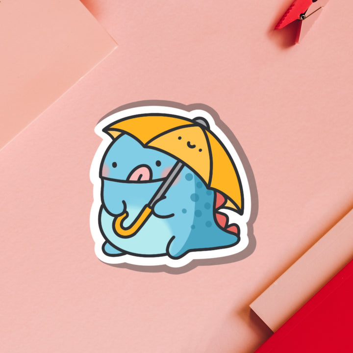 Dinosaur holding umbrella vinyl sticker on pink table