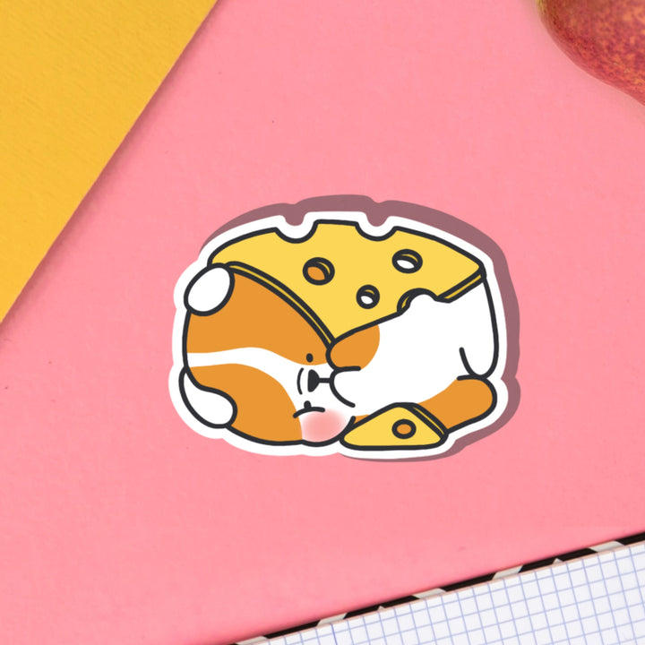 Dog wrapped in cheese vinyl sticker on pink table and notebook