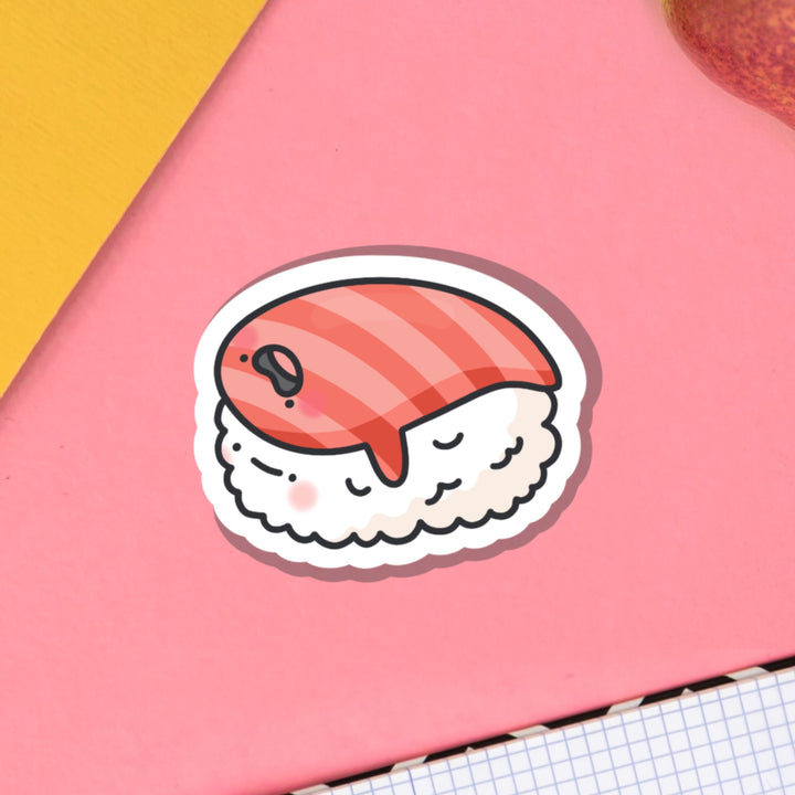 Salmon sushi vinyl sticker on pink table with notebook
