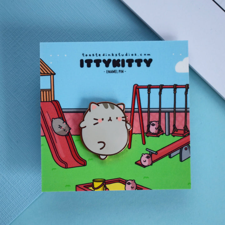 Cat enamel pin on blue background and playground scene backing card