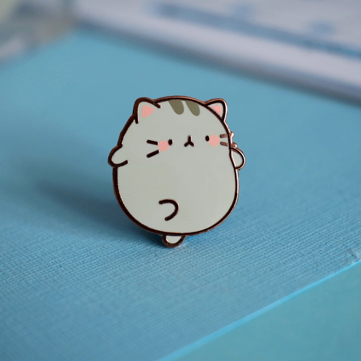Cute kitty enamel pin on blue background table