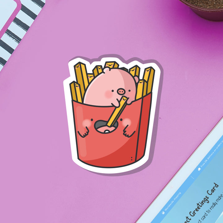 Pig sat in french fries vinyl sticker on purple table and ipad