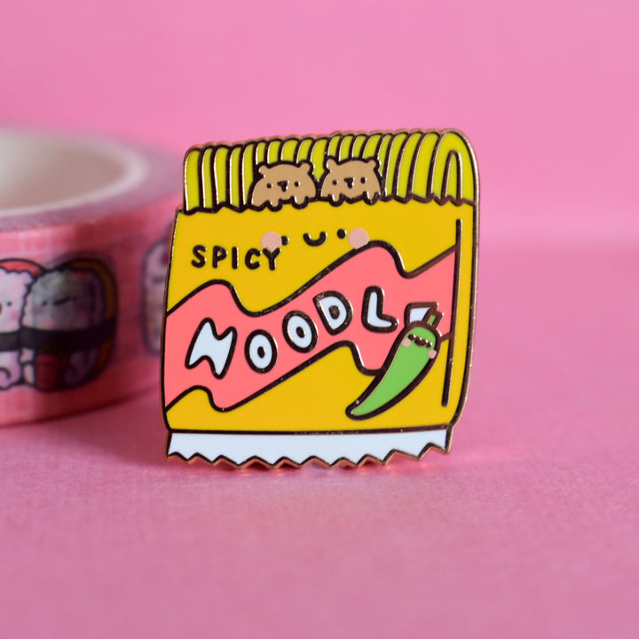 Noodles enamel pin on a pink table