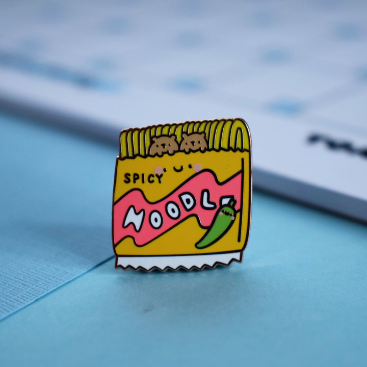 Noodles enamel pin with notepad on blue table