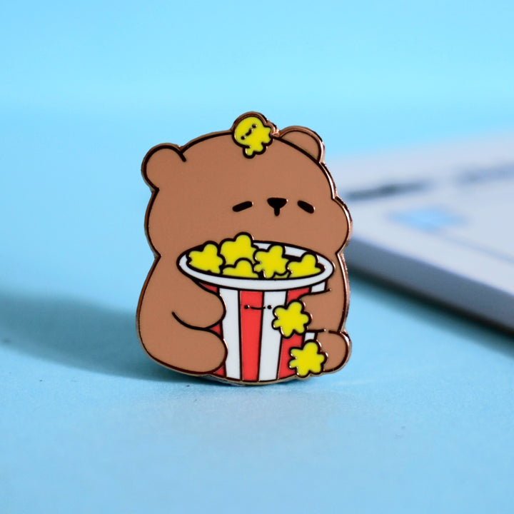Cute popcorn bear enamel pin on blue table