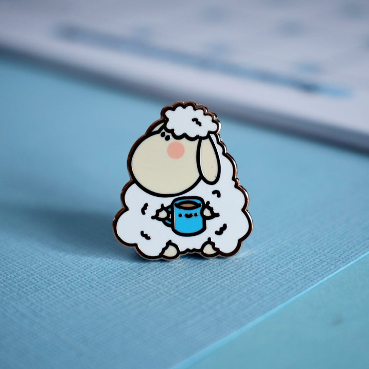 Sheep lapel pin holding mug on blue background