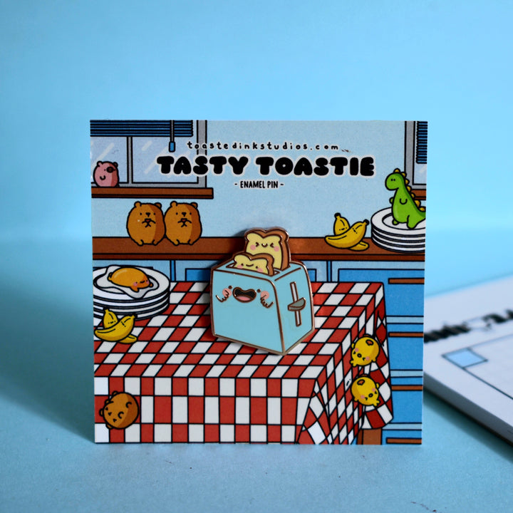 Toaster enamel pin on blue table with notebook