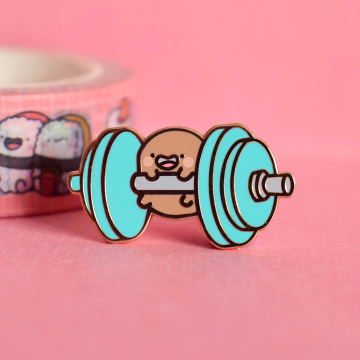 Potato lifting weights enamel pin on pink background